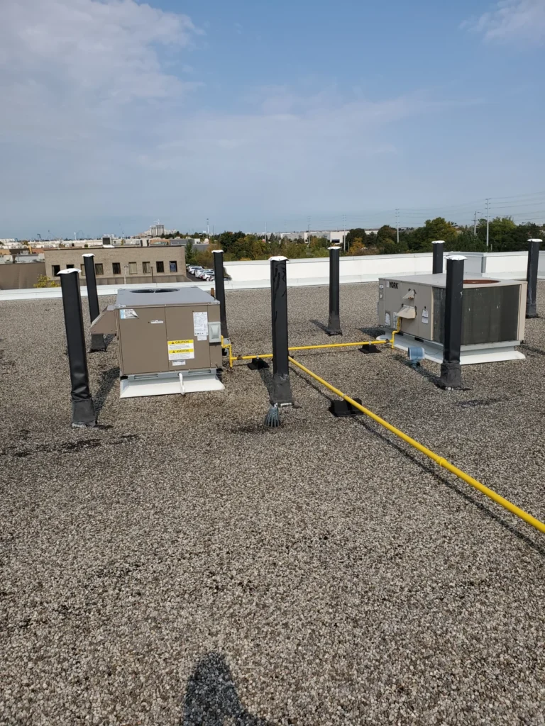 Two commercial rooftop HVAC units with insulated pipes and gas piping